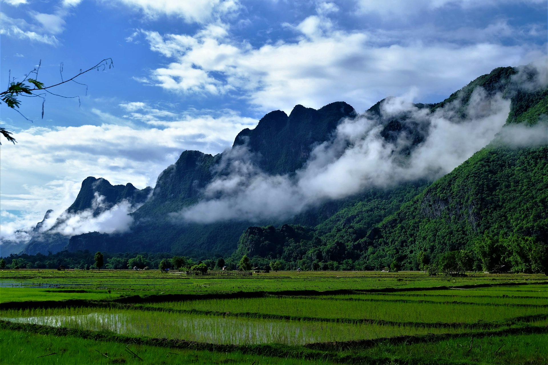 green grass field near mountain under white clouds during daytime